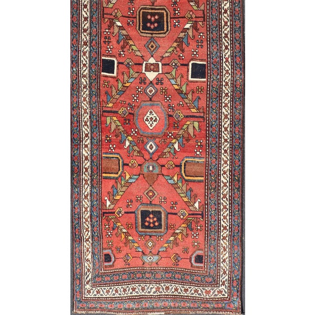 Measures; 3'3 x 14'1 This early 20th century antique Kurdish runner features a triple-lined floral border, emboldening an...