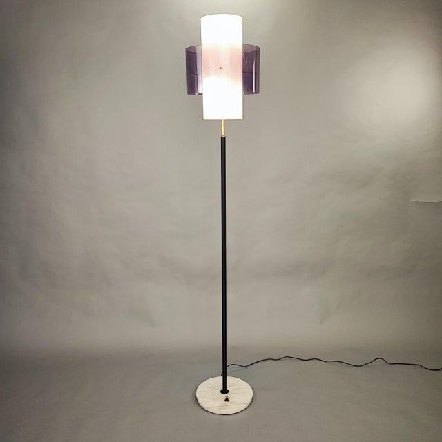 Vintage floor lamp with a purple shade, featuring a minimalist 1970s design. It features a thin metal stem resting on a...
