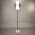 Vintage floor lamp with a purple shade, featuring a minimalist 1970s design. It features a thin metal stem resting on a...