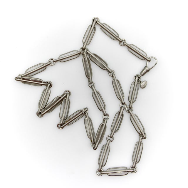 A beautiful variation of a trombone link, rendered in sterling silver and culminating with a dog clip. The chain consists...