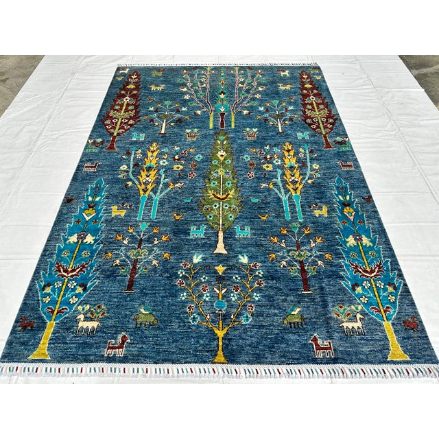 This hand-knotted Afghan pictorial rug arranges borderless rows of cypress, willow, and flowering trees in burgundy, teal,...