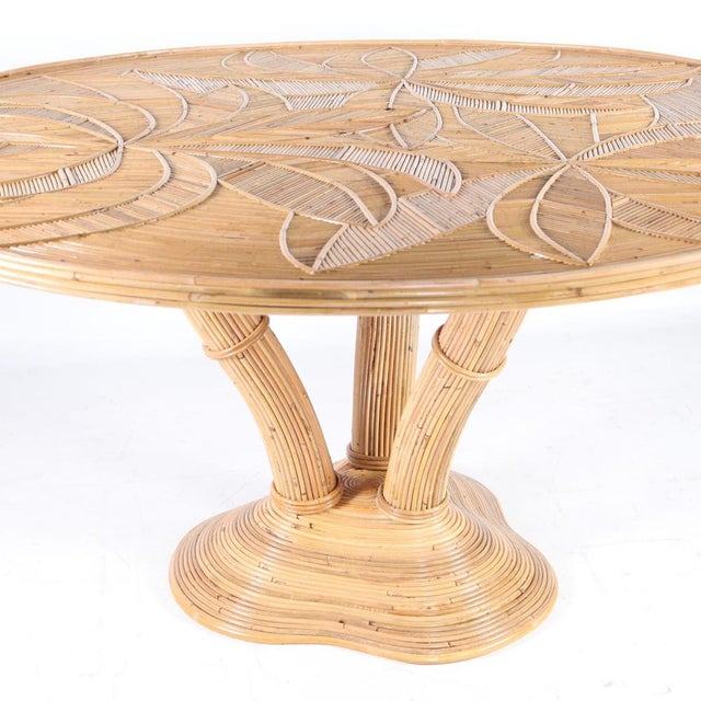 Exceptional round rattan dining table. Legs representing a palmtree, top with palms patterns covered with a glass top....