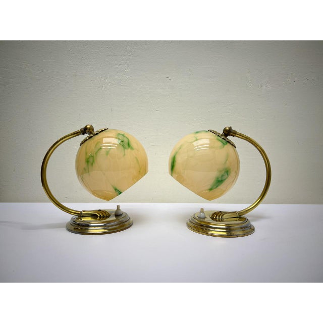 A set of Art Deco table lamps or bedside lamps made of brass in elegant shapes with green clouded opaline round...