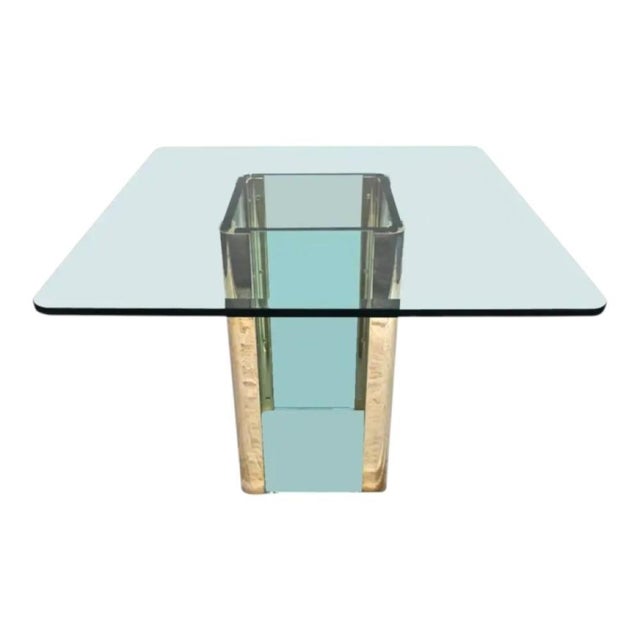 A vintage glass and brass dining table designed by the Pace Collection, featuring a central glass pedestal base held...
