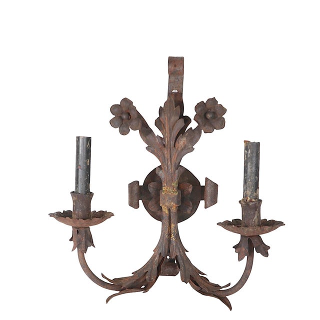 Pair of wrought iron sconces each having two arms, each with a separate candle arm. The structure features decorative...