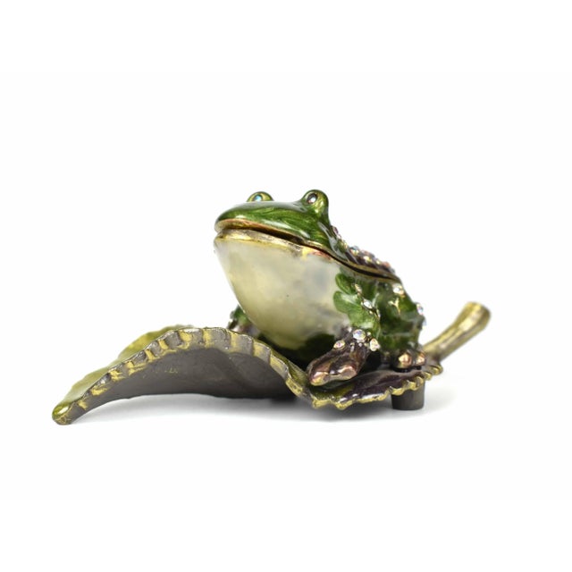Late 20th century jeweled small frog figurine trinket box. It has a hinged compartment which opens for storage. Embedded...