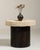 A compact side table combining a heavy stone top with a simple iron cylindrical base, reflecting a blend of utilitarian...