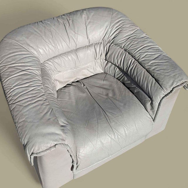Italian leather lounge chair by Natuzzi with a low, rounded postmodern profile and light gray upholstery. The chair has a...