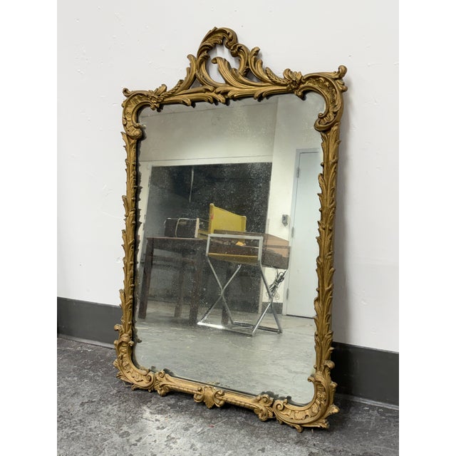 Design Plus Gallery presents an Antique Louis XV Style Gilt Mirror. The mirror has an ornate gilt frame with scrolling...