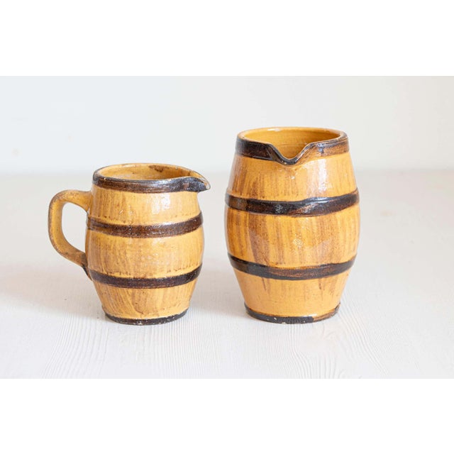 Two rustic French pottery pitchers from the 19th century, with yellow glaze, brown accents and back handles. They are...
