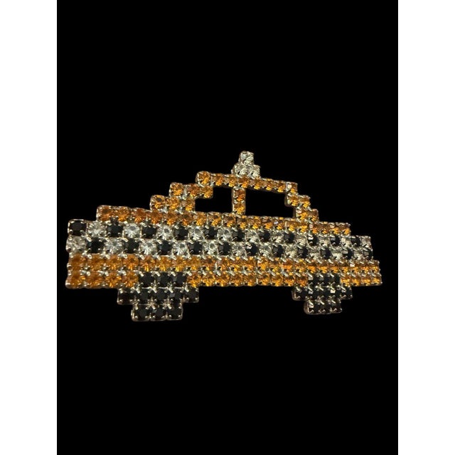 This is a vintage Bauer rhinestone brooch pin designed in the shape of a yellow taxi cab with amber, clear, and black...