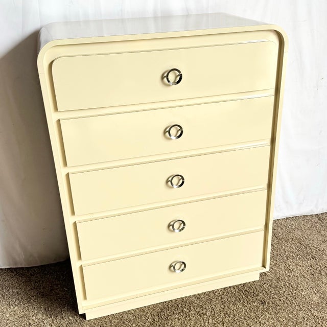 This postmodern highboy dresser features a sleek cream lacquer laminate finish and signature waterfall edges that embody...