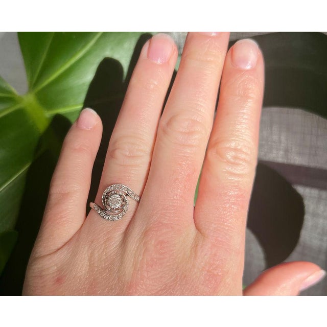 A delicate and intricate swirl ring from the Belle Époque era (circa 1900), crafted in platinum. At its center, it...