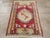 A vintage Turkish Ghiordes throw rug. A lopsided oval old ivory medallion contains a four rose and stem device, on a red...