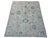Light blue floral medallions and delicate scrolling vines decorate the cream field of this handmade Oushak wool rug....
