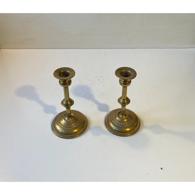 A pair of brass candlesticks for regular sized candles. Distinct functionalist styling with architectural features....