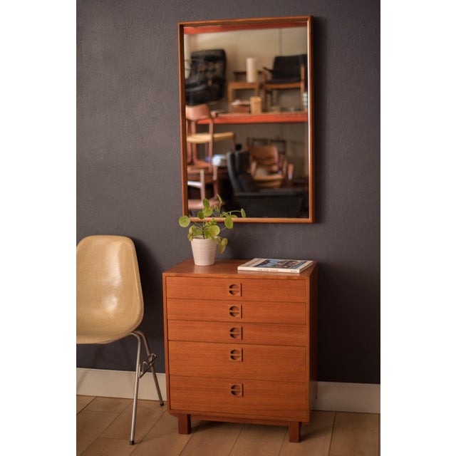 Mid Century Modern accent hanging wall mirror in teak circa 1960s. This versatile piece displays a contoured natural wood...