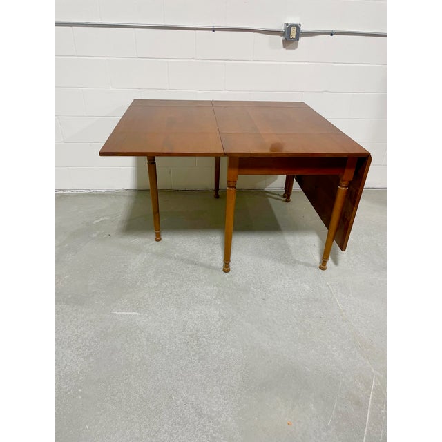 This Stickley Furniture Company cherry drop-leaf table is dated on the label 1953. This table features a cherry plank top...