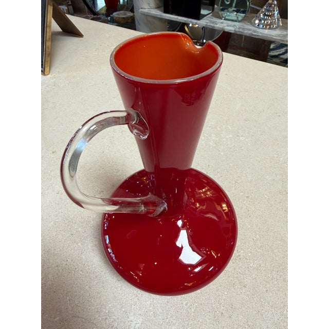 Bold and expressive, this mid-century Italian pitcher is hand-blown in vibrant red Murano glass, showcasing a rich,...