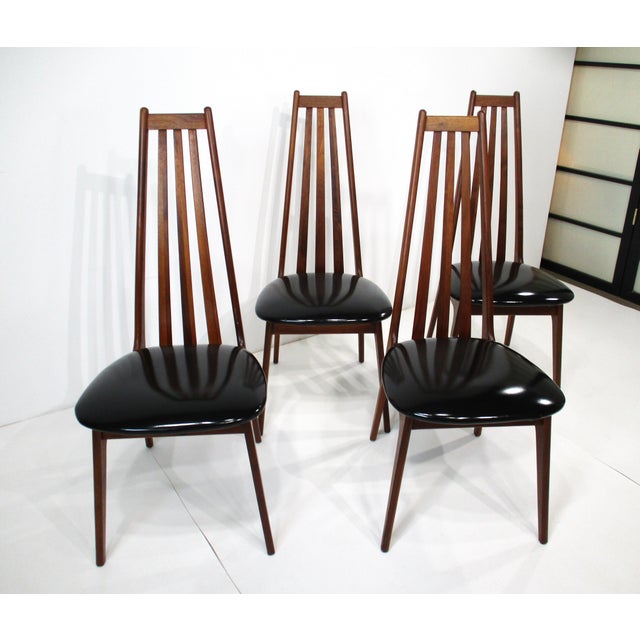 A set of four Mid Century solid walnut framed high back dining chairs retaining their original black patent leather seats....