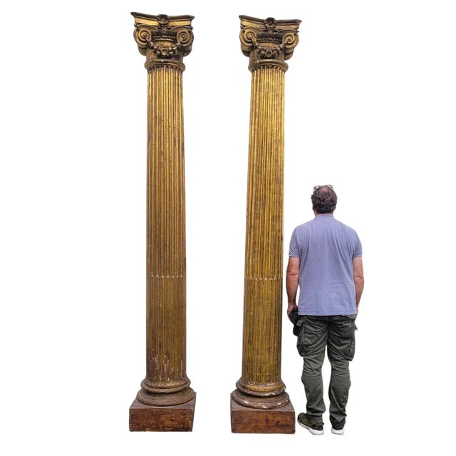 An important pair of carved giltwood columns: the fluted shafts rest on painted wooden bases and are topped with Ionic...