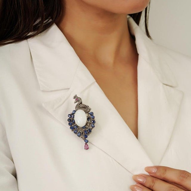 Crafted in 925 sterling silver, this striking peacock brooch pendant features 23.32 carats of opal, blue sapphire, ruby,...