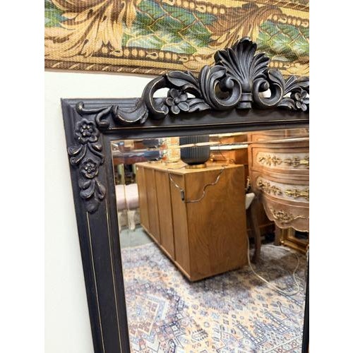 A decorative rectangular mirror with a black painted frame, featuring bevelled glass and an attractive design of scrolling...