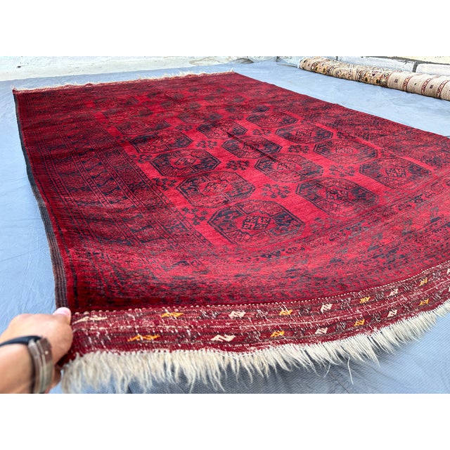 This classic Turkmen Bokhara rug features a bold grid of large elongated octagonal "elephant's foot" guls in deep navy and...