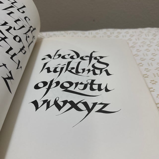 A beautifully illustrated copy of Calligraphic Alphabets by Arthur Baker, a timeless reference for lettering enthusiasts,...