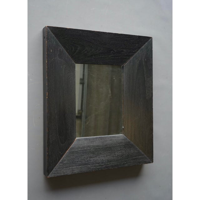 A simple and attractive wall mirror. Its frame is thick solid darkened oak wood.
