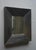 A simple and attractive wall mirror. Its frame is thick solid darkened oak wood.