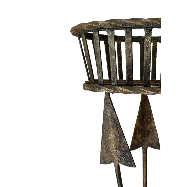 A wonderfully textural wrought iron jardiniere in the regency taste featuring a basket resting upon intersecting arrows...