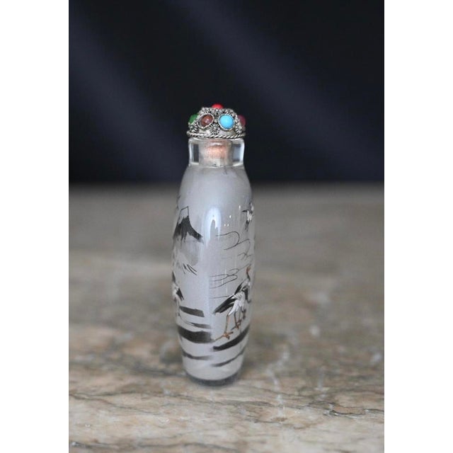 This particular snuff bottle features a meticulously detailed heron motif, capturing the bird's elegance and the...