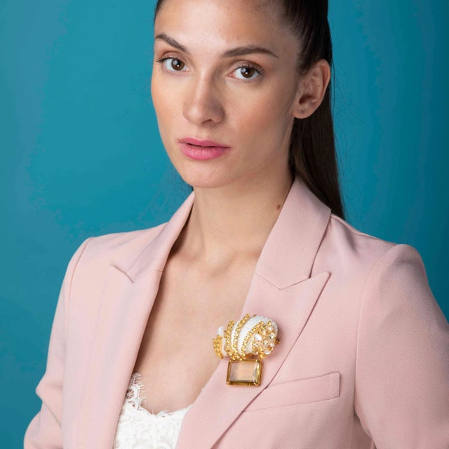The Valentina brooch/pin, fashioned from semi-precious stones, showcases a distinctive shell design that resonates with...
