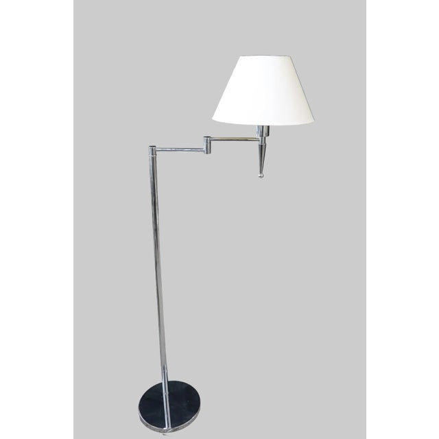 Supported by a circular chrome base, this Mid-Century Modern floor lamp by Casella Lighting features an adjustable...