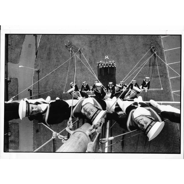 1989 black & white photograph of sailors posing on the mast on the Royal Navy's HMS Daedalus. Publication information on...