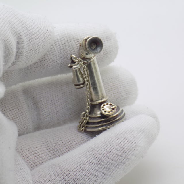 A vintage miniature depicting an antique telephone, handcrafted in silver in Italy between the 1970s and 1980s,...