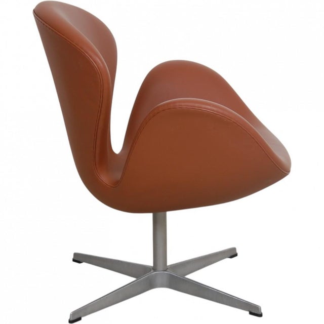 Arne Jacobsen Swan chair upholstered in walnut semi anilin leather, and with a brushed aluminium swivel base. The chair is...