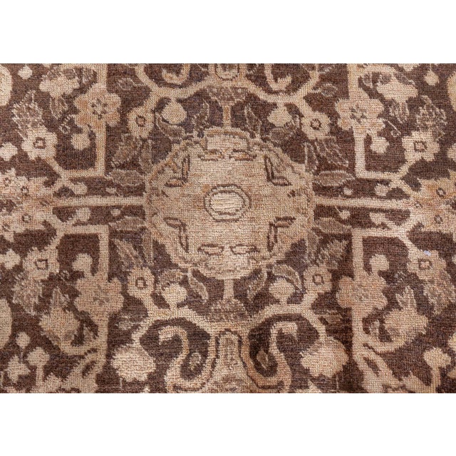 An early 20th century Tabriz Persian rug, the dark brown field with an overall sand-colored trellis of palmettes,...