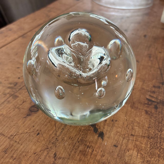 Clear glass round ball paper weight/decorative object with flat base. Very heavy and interesting. I have no knowledge of...