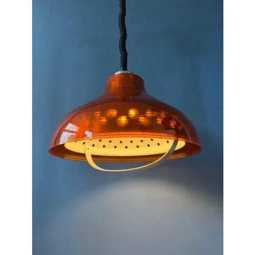 Orange mid century acrylic glass space age pendant lamp. The lamp has an orange outer shade and a patterned aluminium...