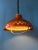 Orange mid century acrylic glass space age pendant lamp. The lamp has an orange outer shade and a patterned aluminium...