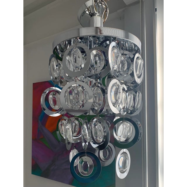 Unique Mid Century Modern Chandelier features Circular chrome bangles, hanging with glass prisms. Fixture is fitted with 3...