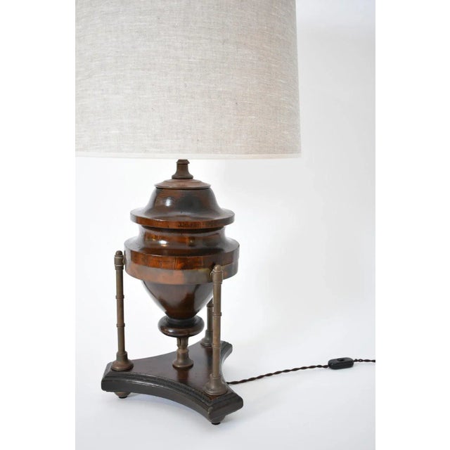 Wood and brass baluster lamp, 1910s. Natural wood baluster-shaped lamp resting on a tripod base with brass uprights...
