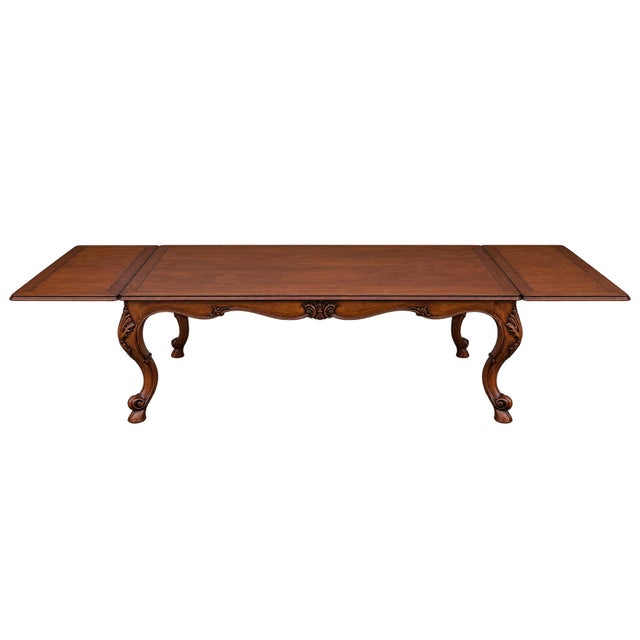 Impeccably crafted French Provincial-style dining table featuring a rich, warm wood finish, gracefully curved cabriole...