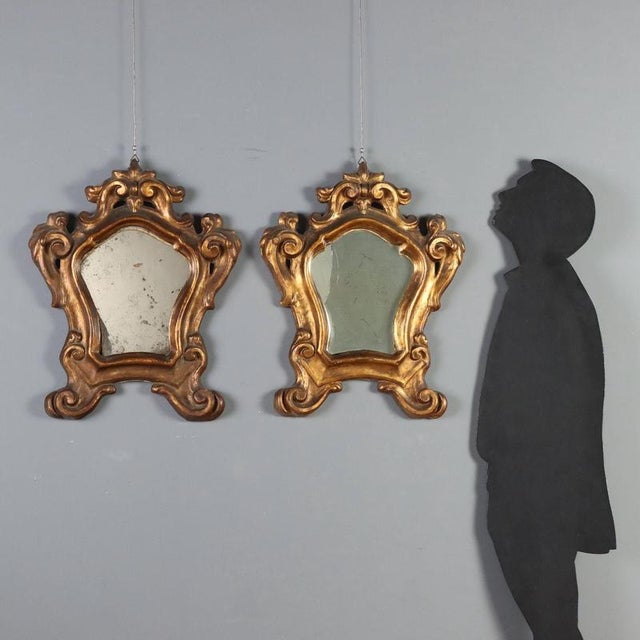 Pair of Baroque mirrors in carved and gilded wood, dating back to the late 18th century in Italy. The molded frames are...