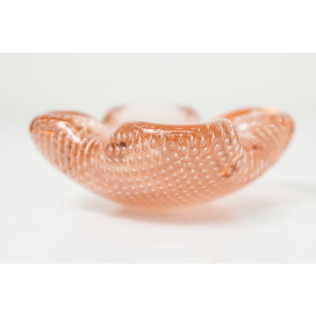 Pastel pink Murano glass ashtray with tiny bubbles inside. Freeform shape. Width and depth 7.5 cm. This piece is...
