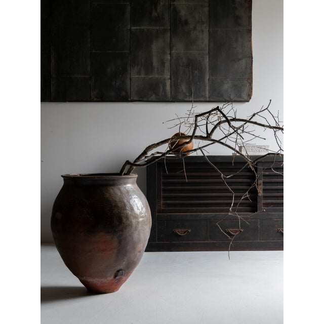 This is a large antique Japanese ceramic jar, embodying a strong sculptural presence shaped by earth, fire, and the...