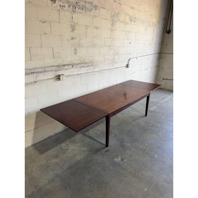 This large dining table features a sleek rectangular top bordered by refined solid edges. The versatile frame incorporates...