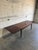 This large dining table features a sleek rectangular top bordered by refined solid edges. The versatile frame incorporates...